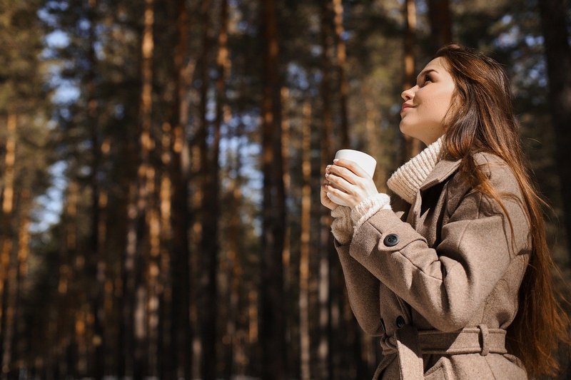 Kobieta z kawą w płaszczu zimowym